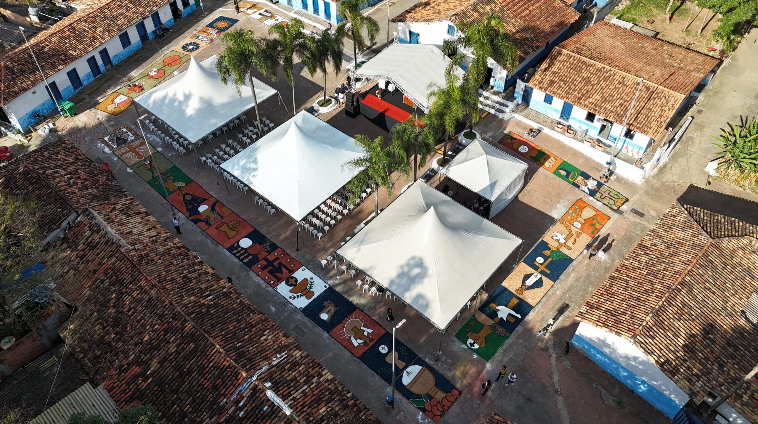 Quinta-feira tem celebração de Corpus Christi na AldeiaA tradicional celebração de Corpus Christi reúne fiéis na praça da Aldeia, nesta quinta-feira, 4 de junho. O evento tem o apoio da Prefeitura e a programação inicia às 9 horas com a confecção dos tapetes coloridos. Os tapetes são produzidos com materiais como serragem colorida, borra de café, sal e flores, e representam símbolos religiosos e passagens bíblicas, confirmando uma expressão artística e de fé que envolve a comunidade local.